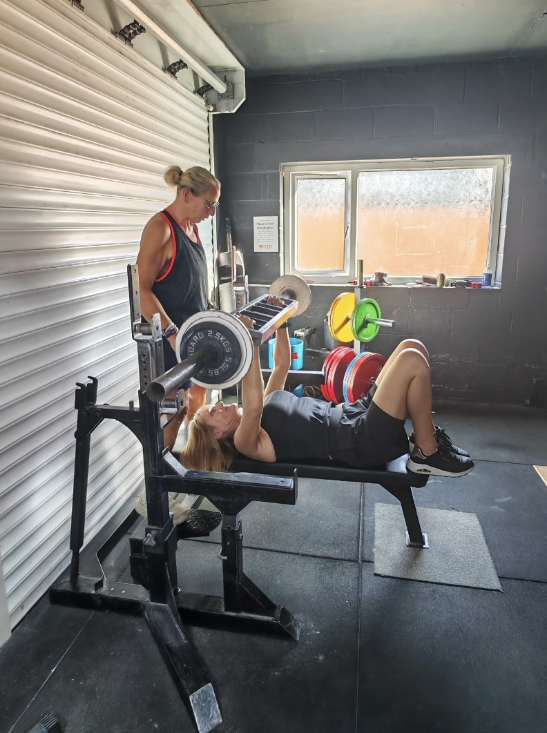 Emma coaching a client during a bench press